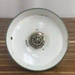 Interior of green enamel ceiling shade with exposed white paint and bulb guard