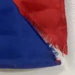 Close-up of damage on vintage maritime Zulu flag, showing a ripped bottom corner and edge wear.