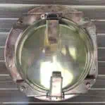 Top-down view of brass pier light highlighting flat side of housing for versatile installation.