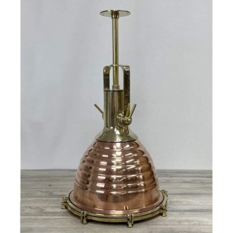 Front view of large brass pendant light on table, highlighting polished brass and copper details