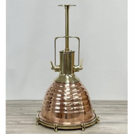 Side view of large brass pendant light on table, showing two-tone brass and copper finish