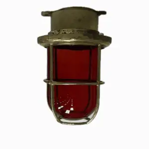 Side view of vintage brass red glass globe ceiling light against white background