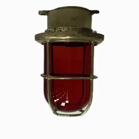 Side view of vintage brass red glass globe ceiling light against white background