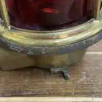 Close-up of patina and wear on vintage brass red glass globe ceiling light and broken leg