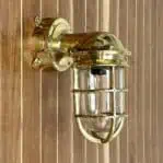 Vintage brass wall sconce mounted on a wall with junction box, showcasing nautical decor style