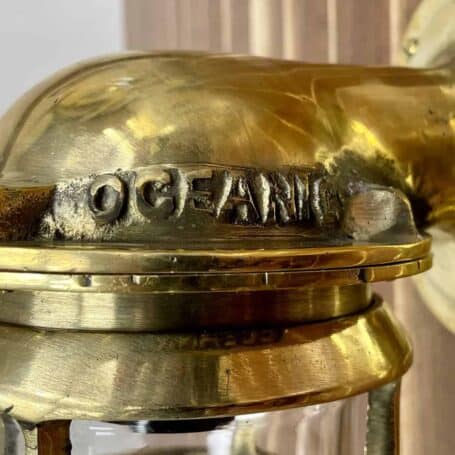 Close-up of the top portion of vintage brass wall sconce, showing the detailed brass cage and glass cover