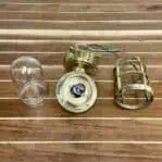 Disassembled view of vintage brass wall sconce with cage, glass cover, and junction box shown separately