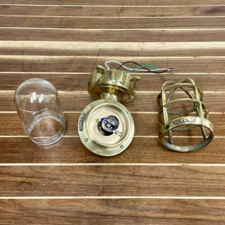Disassembled view of vintage brass wall sconce with cage, glass cover, and junction box shown separately