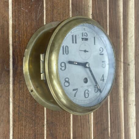 Vintage Brass Nautical Ship Clock - Mechanical Wind-Up (2) Angled view of vintage brass nautical clock mounted on wood background.