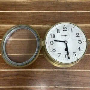 Front view of vintage brass nautical clock with white background