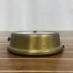 Low profile view of aged brass instrument housing placed on wood surface