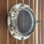 Salvaged Brass Porthole With Screen on a wall