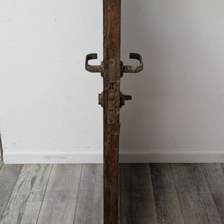Side view of a salvaged ship's door showing weathered hinges and hardware with visible two-tone coloring.