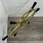 Side view of vintage-style brass ship's wheel with black wooden handles