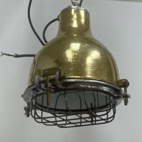 Industrial Caged Brass Plated Pendant Light Industrial caged brass pendant light hanging from chain with exposed wiring.