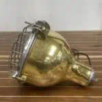 Side view of a vintage brass light with a protective wire cage.