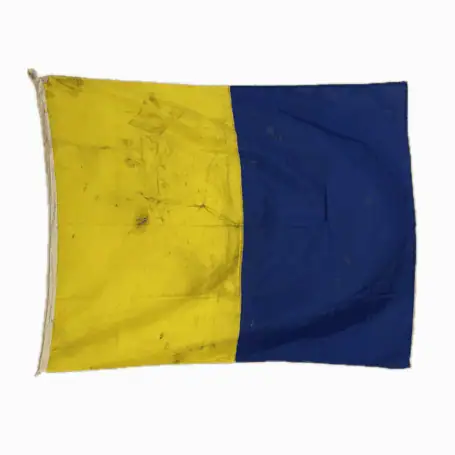 Letter K Kilo nautical signal flag with yellow and blue vertical sections and heavy dirt from sea use