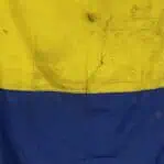 Close-up of dirty Letter K Kilo nautical signal flag showing worn yellow and blue fabric from ship service