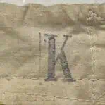 Stamped letter K in blue ink on canvas header of nautical signal flag, showing original ship marking