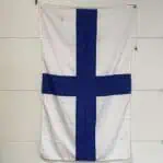 Full view of blue and white cross flag hanging vertically against a wall