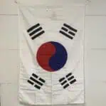 Horizontal view of a large Korean flag with visible stitching and corner grommets for hanging.