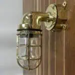 Mounted brass nautical wall sconce with clear globe and polished finish
