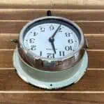 Top angle: Top-down view of vintage marine slave clock with chrome bezel and white face