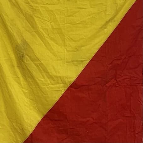 Original Oscar Maritime Signal Flag 01 Original Oscar maritime signal flag showing yellow and red sections with visible service wear and grime