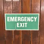Close-up of green and white emergency exit sign on ship door