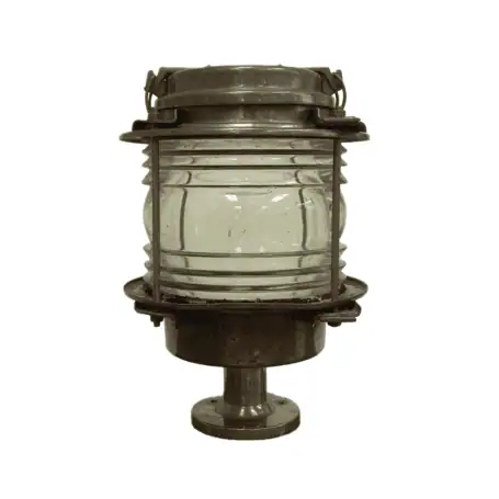 Front view of weathered brass pier light with 360-degree clear glass lens and aged patina. Main photo