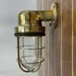 Side view of vintage marine wall sconce installed on wooden panel