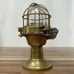 Side view of a vintage nautical post light with red brass midsection and clear glass globe
