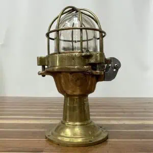 Side view of a vintage nautical post light with red brass midsection and clear glass globe