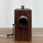 Front view of vintage rotary foghorn showing the hand crank and worn wood surface.