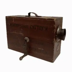 Front view of vintage rotary foghorn showing the hand crank and worn wood surface.