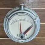 Nautical clinometer by Kompas Rijeka with red and black hands displayed on wood background