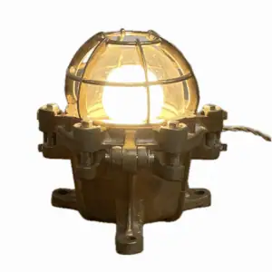 Brass industrial table lamp with glowing bulb on white background
