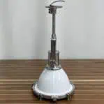 Industrial pendant light with aluminum down rod and white shade shown upright on wood surface