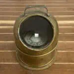 Front view of salvaged brass nautical compass on wood surface