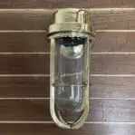 Front view of brass wall sconce showing glass globe and cage