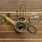 Disassembled parts of brass sconce including cage, glass, and socket