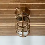Mounted brass nautical ceiling light on wood panel