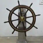 Front view of full vintage ship wheel mounted on base