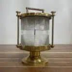 Side view of brass Perko Fresnel light on wood surface