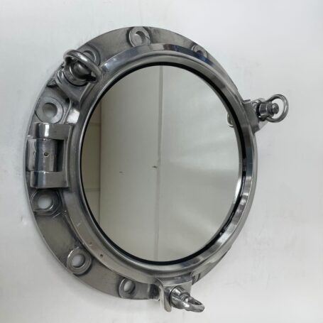Ship porthole mirror mounted on wall showing aluminum frame and three dog locking handles