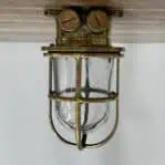 Vintage marine ceiling light mounted to wood surface with visible brass patina