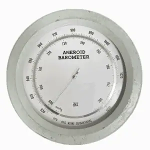 Close-up dial of vintage seafoam green aneroid barometer with dual scale display