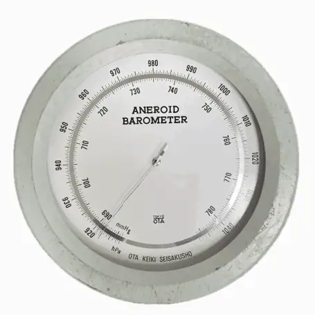 Close-up dial of vintage seafoam green aneroid barometer with dual scale display
