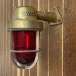 Mounted weathered brass wall sconce with red globe showing WISKA stamp