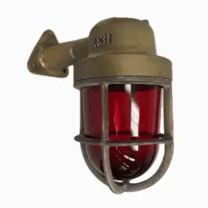 Close-up of weathered brass wall sconce with red glass globe